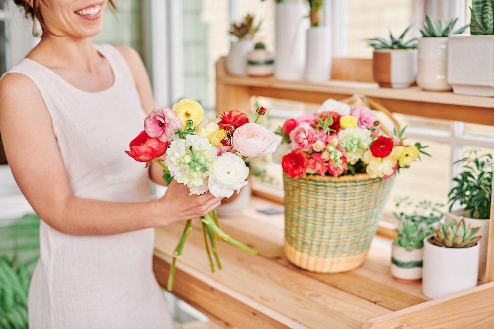 Florist smiling and assembling flowers for delivery